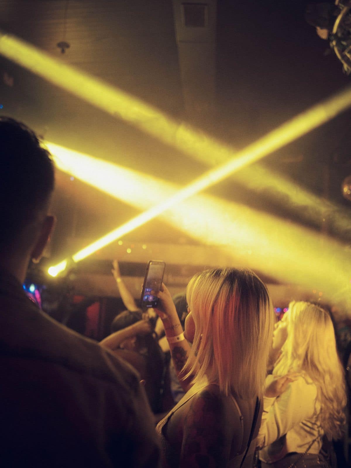 Publikum in einem Club, Lichtstrahlen kreuzen sich über den Köpfen.