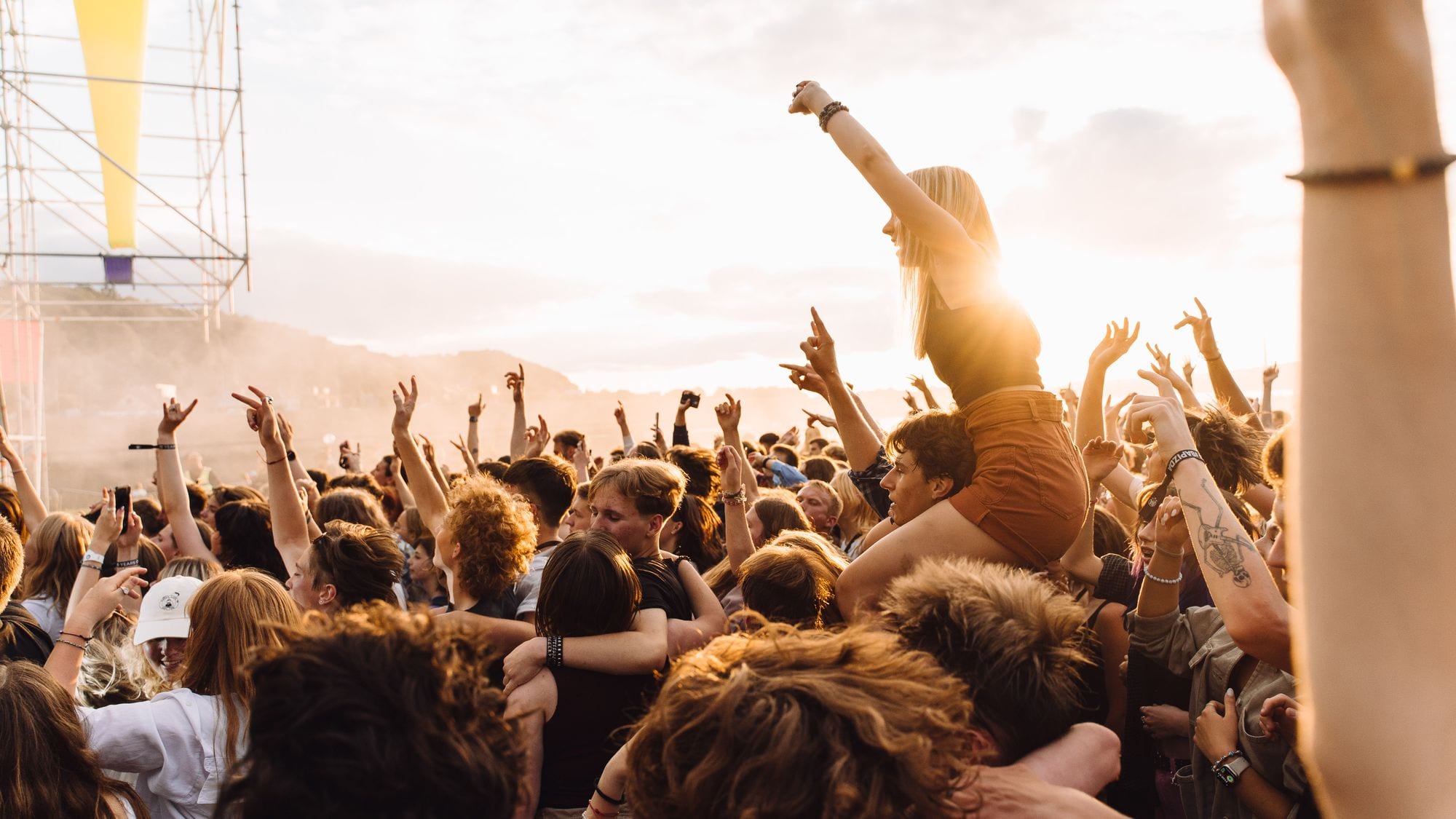 Feiernde Menge bei einem Open-Air-Konzert im Gegenlicht der Abendsonne.